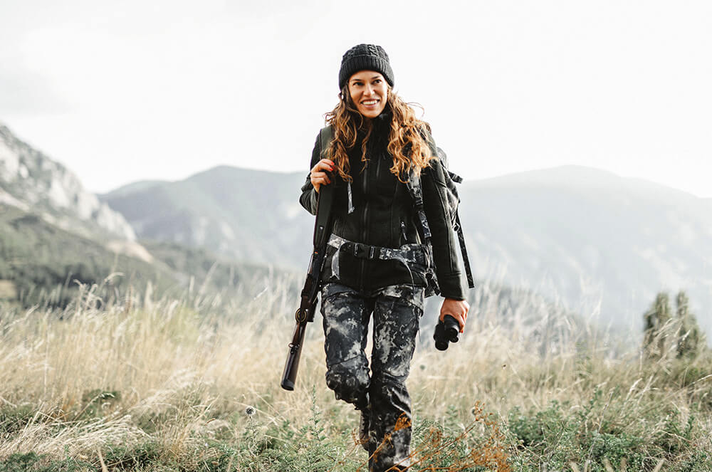 Mujer andando por el campo con un rifle